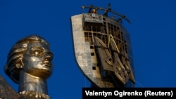 Para pekerja mengangkat lambang nasional Ukraina sebelum memasangnya ke perisai monumen 'Ibu Pertiwi' menggantikan lambang Soviet, di Kyiv, Ukraina 6 Agustus 2023. (Foto : REUTERS/Valentyn Ogirenko)