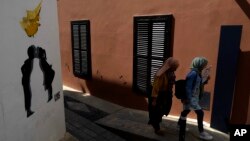 ILUSTRASI - Para migran berjalan di dalam inti abad pertengahan di kota tua ibu kota Nicosia yang terpecah, Siprus, Rabu, 10 Mei 2023. (AP/Petros Karadjias)