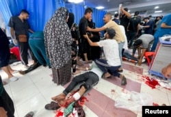 UZNEMIRAVAJUĆA FOTOGRAFIJA - Ludi stoje pored Palestinca ranjenog u izraelskog vazdušnom udaru, u bolnici Šifa, u gradu Gaza, 23. oktobra 2023.