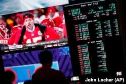 Osoba se kladi na Superboul utakmicu američkog fudbala, 3. februara 2023. u Las Vegasu. Na jednom monitoru su izlistane kvote, a na drugom se emituje sportski program. Informacije o klađenju sada su sastavni dio sportskih emisija i prenosa utakmica. (Foto: AP/John Locher)
