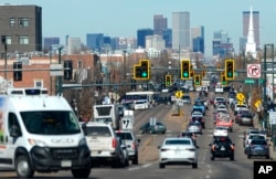 FILE - Motorists move northbound along South Broadway as the skyline of Denver stands as a backdrop in Englewood, Colorado, Feb. 12, 2024.