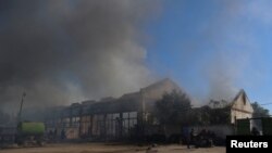 Petugas pemadam kebakaran dan polisi berusaha memadamkan api di sebuah gudang yang hangus terbakar akibat serangan pasukan Rusia di Kherson, Ukraina, pada 19 September 2023. (Foto: Reuters/Ivan Antypenko)