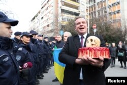 Advokat Čedomir Stojković, proukrajinski aktivista u Srbiji, isporučuje krvavu tortu i lobanju policiji koja čuva rusku ambasadu u Beogradu, na godišnjicu ruske invazije Ukrajine u Beogradu, Srbija, 24. februara 2023. (Foto: Rojters,/Zorana Jevtić)