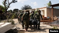 Tentara Israel membawa jenazah korban serangan militan dari Gaza di Kibbutz Kfar Aza, di Israel selatan, Selasa 10 Oktober 2023.