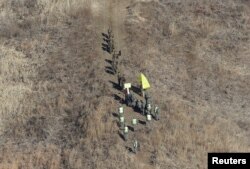 Tentara Korea Utara, atas, melintasi Garis Demarkasi Militer di dalam Zona Demiliterisasi (DMZ) untuk memeriksa pos penjagaan Korea Selatan yang dibongkar, 12 Desember 2018. (Foto: via Reuters)