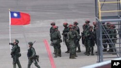 FILE - Seorang tentara Taiwan memegang bendera nasional Taiwan dalam latihan militer tahunan Han Kuang di lapangan terbang di Bandara Internasional Taoyuan di Taoyuan, Taiwan Utara , 26 Juli 2023. (AP/Chiang Ying-ying) File)