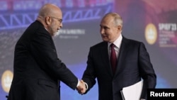 资料照片：俄罗斯总统弗拉基米尔·普京在圣彼得堡国际经济论坛的一次会议期间与主持人德米特里·西姆斯握手。(2023年6月16日)