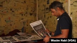 A member of The Kashmir Walla staff looks at old copies of the newspaper on Aug. 21, 2023, as staff clear the newsroom after being served an eviction notice.