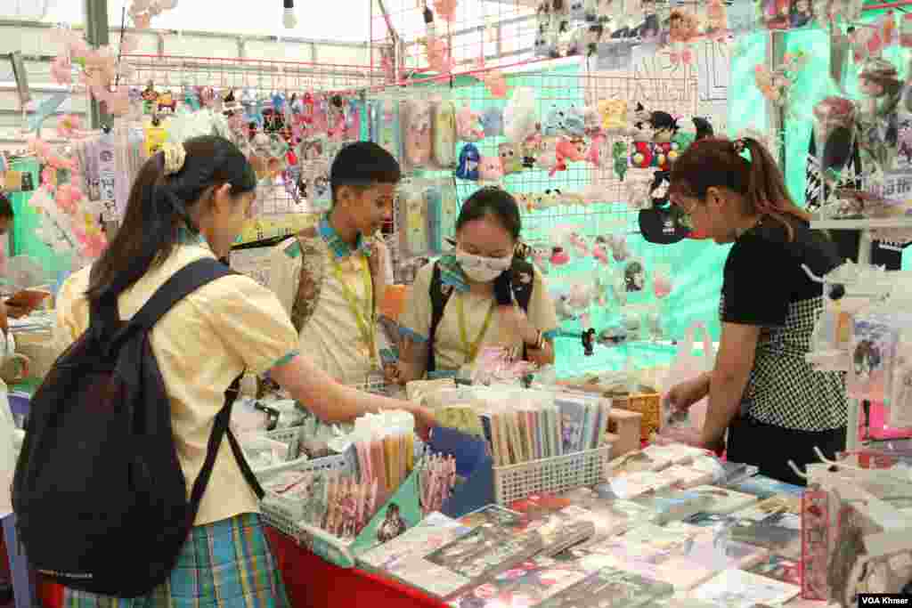 សិស្ស​សាលា​មួយ​ក្រុម​កំពុង​ឈរ​ទិញ​សៀវភៅនិង​សម្ភារៈ​មួយ​ចំនួន​ក្នុង​ស្តង់​សៀវភៅ​ក្នុង​កម្មវិធី​ពិព័រណ៌​សៀវភៅ​ក្នុង​ទិវា​ជាតិ​អំណាន​លើក​ទី​៩ នៅ​វិទ្យាស្ថានបច្ចេកវិទ្យាកម្ពុជា ក្នុង​រាជធានី​ភ្នំពេញ នាថ្ងៃទី​៩ ខែ​មីនា ឆ្នាំ​២០២៤។ (ស៊ឹម ចាន់សំណាង/វីអូអេ)