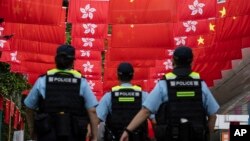香港警察在香港主权移交中国27年纪念日走过挂满中国国旗和香港旗帜的街道。（2024年7月1日）