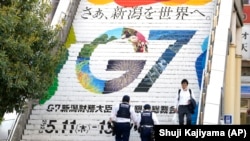 Petugas kepolisian menaiki tangga stasiun yang berlogo pertemuan G7, di Niigata, Jepang, Rabu, 10 Mei 2023. (Foto: AP)