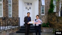 “29原则”执行总监叶七轮(Chakra Ip，右)代表85个人权组织将联署信递交老挝驻英国大使馆职员。（美国之音/郑乐捷）