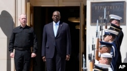 Defense Secretary Lloyd Austin, standing right, and Israeli Defense Minister Yoav Gallant, standing left, listen to the playing of the Israeli National Anthem during an arrival ceremony at the Pentagon in Washington, June 25, 2024.