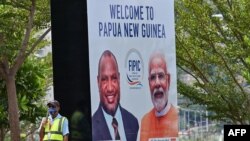 Seorang petugas keamanan berdiri di samping spanduk yang menampilkan Perdana Menteri Papua Nugini (kiri) dan Perdana Menteri India Narendra Modi di ibu kota Port Moresby, Papua Nugini, 18 Mei 2023. 