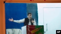 Mantan perdana menteri Pakistan, Imran Khan, berpidato di hadapan para pendukungnya dari balik penghalang anti peluru, di Lahore, Pakistan, Minggu, 26 Maret 2023. (Foto: K.M. Chaudary/AP Photo)