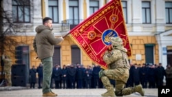 Ukrajinski predsednik Volodimir Zelenski drži zastavu vojne jedinice dok je oficir ljubi tokom komemorativnog događaja povodom godišnjice rata između Rusije i Ukrajine u Kijevu, Ukrajina, 24. februara 2023.