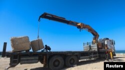 Seorang pekerja Palestina menyiapkan sejumlah beton yang akan digunakan untuk membangun dermaga sementara di Khan Younis, Jalur Gaza, pada 12 Maret 2024. (Foto: Reuters/Ahmed Zakot)