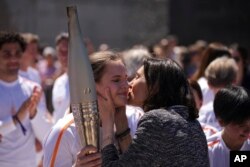 French Sports Minister Amelie Oudea-Castera, right, kisses Maria Vysotchanska of Ukraine on the cheek during the Olympic torch relay in Marseille, southern France, May 9, 2024.