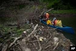 Para sukarelawan mengumpulkan sampah dari tepi sungai Tisza dekat Tiszaroff, Hungaria, Selasa, 1 Agustus 2023. (AP/Denes Erdos)