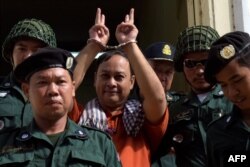 FILE - Nay Vanda (C), a Cambodian senior officer from the local rights group The Cambodian Human Rights and Development Association (ADHOC), is escorted by police officials outside the Appeal court in Phnom Penh on August 30, 2016.