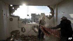 Warga Palestina mengumpulkan barang-barang mereka dari rumah mereka yang rusak pasca serangan udara Israel di Rafah, Jalur Gaza selatan, 27 Januari 2024. (Foto: AP)