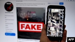 ILUSTRASI - Layar ponsel menampilkan gambar tim SAR tengah bekerja di bangunan tempat tinggal yang hancur akibat serangan rudal di Dnipro, 16 Januari 2023, dan situs web WarOnFakes.com menampilkan video palsu di latar komputer. (OLIVIER DOULIERY / AFP)