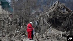 Medicinski radnik teši ženu ispred mesta ruskog vazdušnog udara, u Zaporožju, Ukrajina, 22. marta 2024.