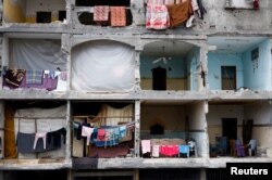 Seorang perempuan duduk di rumahnya yang hancur di Rafah, di selatan Jalur Gaza, 22 Maret 2024. (Foto: Reuters)