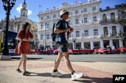 Wisatawan berjalan di sepanjang jalan di Havana, 20 Desember 2023. (YAMIL LAGE / AFP)