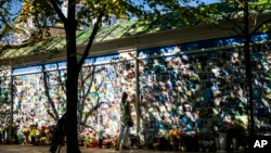 Seorang perempuan menyentuh foto seorang tentara Ukraina di dinding peringatan tentara Ukraina yang tewas selama perang, di katedral Saint Michael di Kyiv, Ukraina, 8 Mei 2024.