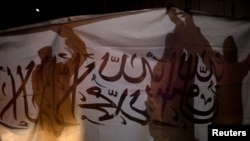 FILE - Taliban supporters hold an Islamic Emirate of Afghanistan flag during a rally in Kabul, Afghanistan, Aug. 30, 2022.