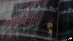 FILE - A migrant looks out the window on a bus on her way north to Nicaragua and hopefully to the Mexico-United States border, in Paso Canoas, Costa Rica, Oct. 16, 2023.