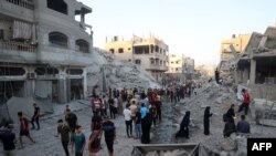 Palestinians gather to check a building shortly after it was leveled by Israeli bombing in the Nuseirat refugee camp in the central Gaza Strip, Aug. 22, 2024.