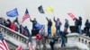 FILE — Rioters wave flags on the West Front of the U.S. Capitol in Washington on Jan. 6, 2021. The federal judge assigned to the election fraud case against former President Donald Trump stands out as one of the toughest punishers of rioters who stormed the U.S. Capitol that day.