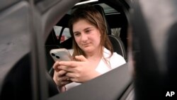 Alexis Bogan, whose speech was impaired by a brain tumor, uses an AI powered smartphone app to create a audible drink order at a Starbucks drive-thru, April 29, 2024, in Lincoln, R.I. 