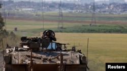 An Israeli soldier gestures, as he rides in an armored personnel carrier (APC), near the Israel-Gaza border, in Israel, March 10, 2024. 