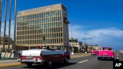 FILE - Tourists in classic cars pass the U.S. Embassy in Havana, Oct. 3, 2017. A Senate report on Dec. 27, 2024, criticized the CIA's response to Havana syndrome health problems. 