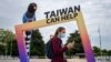FILE - A woman walks by an arch reading "Taiwan can help" next to the building of the United Nations Offices in Geneva on the opening day of the WHO's World Health Assembly in Geneva, on May 24, 2021. 