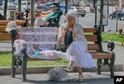 Seorang perempuan duduk di bangku dan merajut saat menikmati hari pada musim gugur yang hangat di Khreshchatyk Avenue, ibu kota Ukraina, Kyiv, Kamis, 8 September 2016. (AP/Efrem Lukatsky)