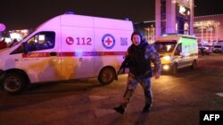 Policajac viče na prolaznike i reportere ispred hale Krokus siti u predgrađu Moskve, gde se dogodio napad (Foto: AFP)