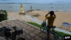 资料照：一名男子在中国厦门用一副望远镜隔海遥望台湾金门岛。（2022年8月3日）