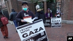 FILE - George Stevens of Cambridge, Mass., hands out leaflets to passers-by near an entrance to Harvard University, Dec. 12, 2023, in Cambridge, while joining with pro-Palestinian demonstrators during a protest held to call for an end to the war in Gaza.
