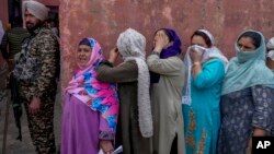 Kashmiri women hide their faces from cameras as they wait outside a polling station to cast their votes during the fourth phase of India's national elections, on the outskirts of Srinagar, Indian-administered Kashmir, May 13, 2024.