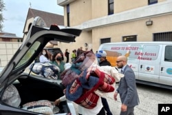 FILE - Officials transport new blankets into St. Anthony Croatian Catholic Church, which was hosting newly bused migrants in Los Angeles, California, on June 14, 2023.