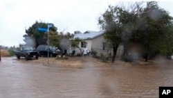 A resident checks flood waters surrounding his home during a downpour in Palmdale, California, as a tropical storm moves into the area, Aug. 20, 2023.