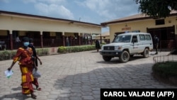 Deux femmes passent devant une ambulance à l'hôpital Nzérékoré le 24 février 2021. AFP / Carol valade 