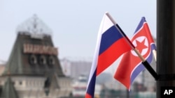 FILE - Flags of Russia and North Korea are seen in front of the central railway station in Vladivostok, Russia, April 24, 2019. A South Korean missionary who reportedly worked with North Korean laborers in Vladivostok has been accused of espionage, according to media reports. 