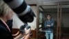 Reporter Wall Street Journal Evan Gershkovich berdiri di dalam sangkar kaca saat fotografer memotretnya di ruang sidang Pengadilan Kota Moskow, di Moskow, Rusia, 18 April 2023. Seorang wartawan Rusia menceritakan saat dia diracun Pemerintah Rusia. (Foto: AP)
