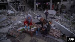 Keluarga Al-Naji bersiap untuk berbuka puasa di hari pertama bulan suci Ramadan sambil duduk di tengah reruntuhan rumah keluarga mereka di Deir el-Balah, Jalur Gaza tengah, Senin 11 Maret 2024. 