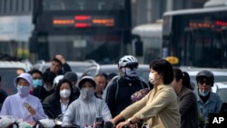 Para komuter tampak menggunakan masker ketika melewati distrik bisnis di Beijing, pada 26 Mei 2023. (Foto: AP/Mark Schiefelbein)